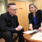 Susan Torborg speaks with a priest