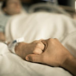 man holding woman's hand hospital bed