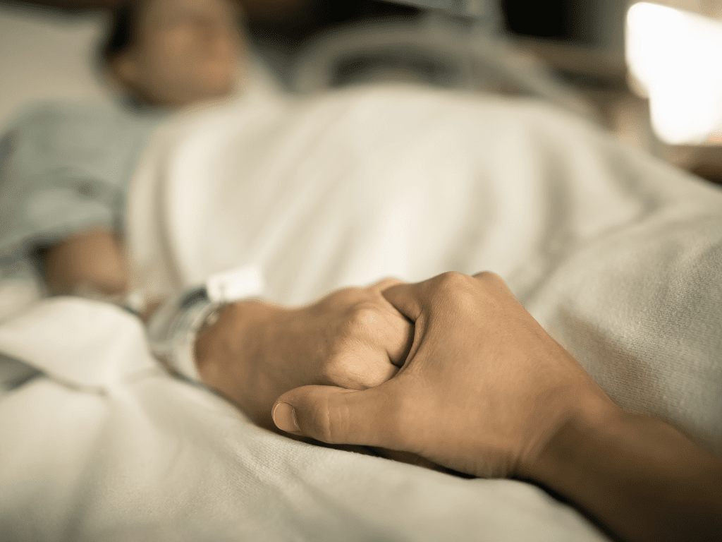 man holding woman's hand hospital bed